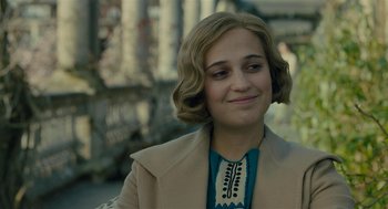 Movie still from “The Danish Girl” (2015), directed by Tom Hooper – A young woman with blonde curly hair wearing a beige coat; Close Up shot, Over the shoulder angle