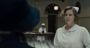 Movie still from “The Danish Girl” (2015), directed by Tom Hooper – A woman in a nurse's uniform in front of two other women; Close Up shot, Over the shoulder angle