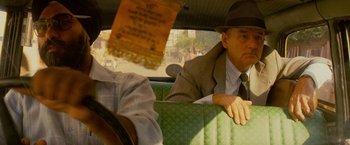 Movie still from “The Darjeeling Limited” (2007), directed by Wes Anderson – A man sitting in the back seat of a green car; Close Up shot, Over the shoulder angle