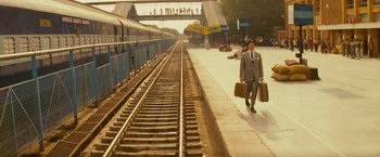 Movie still from “The Darjeeling Limited” (2007), directed by Wes Anderson – A man in a suit and tie walking down a train platform; Extreme Wide shot, High angle