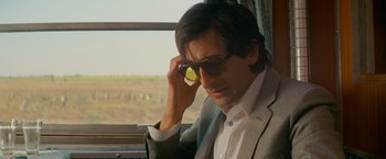 Movie still from “The Darjeeling Limited” (2007), directed by Wes Anderson – A man in a suit and sunglasses looking out of a window; Close Up shot, Over the shoulder angle
