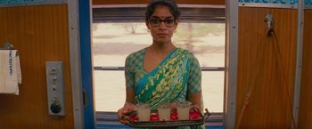 Movie still from “The Darjeeling Limited” (2007), directed by Wes Anderson – A woman holding a tray with drinks on top of it; Medium shot, Over the shoulder angle