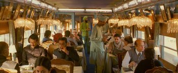 Movie still from “The Darjeeling Limited” (2007), directed by Wes Anderson – A group of people sitting at a table in a restaurant; Wide shot, High angle