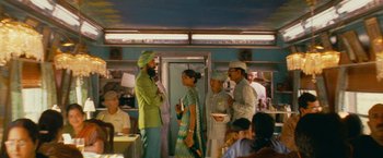 Movie still from “The Darjeeling Limited” (2007), directed by Wes Anderson – A group of people standing in a room; Wide shot, Over the shoulder angle