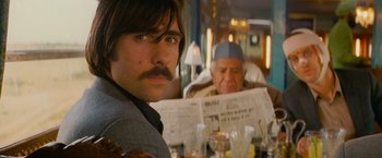 Movie still from “The Darjeeling Limited” (2007), directed by Wes Anderson – A man sitting at a table in front of an older man; Close Up shot, Over the shoulder angle