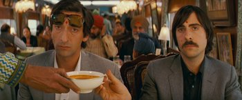 Movie still from “The Darjeeling Limited” (2007), directed by Wes Anderson – A man holding a bowl of soup in his hand; Close Up shot, Over the shoulder angle