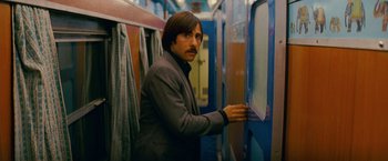 Movie still from “The Darjeeling Limited” (2007), directed by Wes Anderson – A man standing in a room next to a door; Medium shot, Over the shoulder angle
