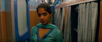 Movie still from “The Darjeeling Limited” (2007), directed by Wes Anderson – A woman in a blue dress standing in a room; Close Up shot, Low angle