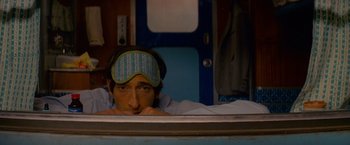 Movie still from “The Darjeeling Limited” (2007), directed by Wes Anderson – A man wearing a sleep mask is laying in a bed; Close Up shot, High angle