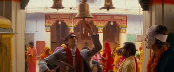 Movie still from “The Darjeeling Limited” (2007), directed by Wes Anderson – A man is ringing a bell at a religious ceremony; Medium shot, Low angle