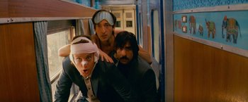 Movie still from “The Darjeeling Limited” (2007), directed by Wes Anderson – A group of men standing next to each other on top of a train; Medium shot, Low angle