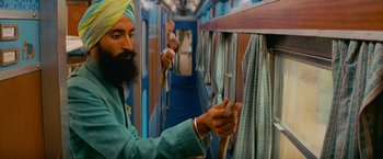 Movie still from “The Darjeeling Limited” (2007), directed by Wes Anderson – A man with a beard and a yellow turban on a train; Medium shot, Low angle
