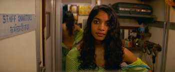 Movie still from “The Darjeeling Limited” (2007), directed by Wes Anderson – A woman with long black curly hair looking at a mirror; Close Up shot, Over the shoulder angle