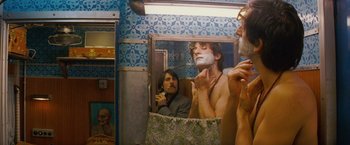 Movie still from “The Darjeeling Limited” (2007), directed by Wes Anderson – A man shaving in front of a bathroom mirror; Medium shot, Over the shoulder angle