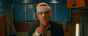 Movie still from “The Darjeeling Limited” (2007), directed by Wes Anderson – A man with a bandage on his head and a bandage on his face; Close Up shot, Over the shoulder angle