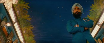 Movie still from “The Darjeeling Limited” (2007), directed by Wes Anderson – A woman standing in front of a sunflower field at night; Medium shot, Low angle