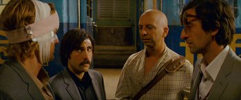 Movie still from “The Darjeeling Limited” (2007), directed by Wes Anderson – Two men standing next to each other in front of a building; Close Up shot, Low angle