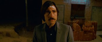 Movie still from “The Darjeeling Limited” (2007), directed by Wes Anderson – A man in a suit with a bandage on his forehead; Close Up shot, Over the shoulder angle