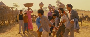 Movie still from “The Darjeeling Limited” (2007), directed by Wes Anderson – A group of people walking down a dirt road; Wide shot, High angle