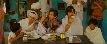 Movie still from “The Darjeeling Limited” (2007), directed by Wes Anderson – A group of people sitting around a table eating food; Medium shot, High angle