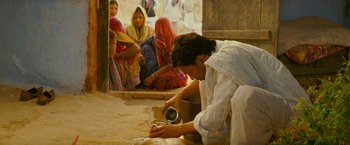 Movie still from “The Darjeeling Limited” (2007), directed by Wes Anderson – A man pouring something into a bowl while people watch; Medium shot, High angle