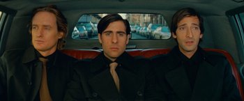 Movie still from “The Darjeeling Limited” (2007), directed by Wes Anderson – A man sitting in the back seat of a car; Close Up shot, Low angle