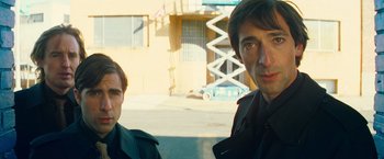 Movie still from “The Darjeeling Limited” (2007), directed by Wes Anderson – Two men standing next to each other in front of a building; Close Up shot, Low angle