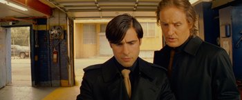 Movie still from “The Darjeeling Limited” (2007), directed by Wes Anderson – A man wearing a black jacket and a yellow tie; Close Up shot, Low angle