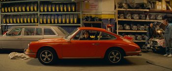 Movie still from “The Darjeeling Limited” (2007), directed by Wes Anderson – A woman sitting in a red car in a garage; Wide shot, High angle