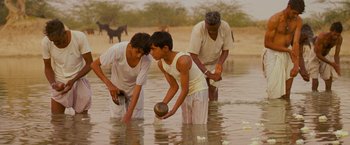Movie still from “The Darjeeling Limited” (2007), directed by Wes Anderson – A group of men standing in shallow water; Medium shot, High angle