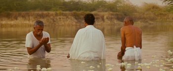 Movie still from “The Darjeeling Limited” (2007), directed by Wes Anderson – A man sitting in a body of water; Medium shot, Over the shoulder angle