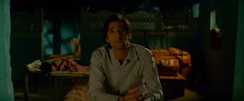 Movie still from “The Darjeeling Limited” (2007), directed by Wes Anderson – A man sitting in front of a fire place; Medium shot, Low angle