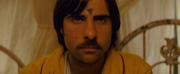Movie still from “The Darjeeling Limited” (2007), directed by Wes Anderson – A person with a cross on his forehead; Close Up shot, Overhead angle
