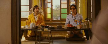 Movie still from “The Darjeeling Limited” (2007), directed by Wes Anderson – Two men sitting in front of plates of food on a table; Medium shot, Low angle