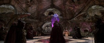 Movie still from “The Dark Crystal” (1982), directed by Frank Oz – A group of people standing in a room with a large purple crystal; Wide shot, High angle
