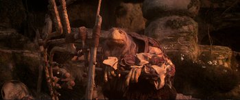 Movie still from “The Dark Crystal” (1982), directed by Frank Oz – A stuffed animal sitting on top of a pile of rocks; Medium shot, Low angle
