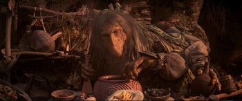 Movie still from “The Dark Crystal” (1982), directed by Frank Oz – An image of an animal that is eating food out of a bowl; Medium shot, Low angle