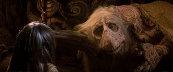 Movie still from “The Dark Crystal” (1982), directed by Frank Oz – An animal with long hair is sitting on a chair; Close Up shot, Low angle