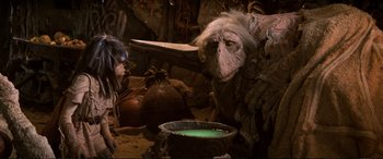 Movie still from “The Dark Crystal” (1982), directed by Frank Oz – An animal that is sitting next to a pot; Medium shot, Over the shoulder angle