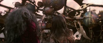 Movie still from “The Dark Crystal” (1982), directed by Frank Oz – A woman standing next to a bunch of metal balls; Medium shot, Over the shoulder angle