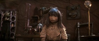 Movie still from “The Dark Crystal” (1982), directed by Frank Oz – A young girl with long brown hair wearing a costume; Close Up shot, High angle