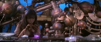 Movie still from “The Dark Crystal” (1982), directed by Frank Oz – A woman sitting in front of a table with a lamp; Medium shot, Low angle