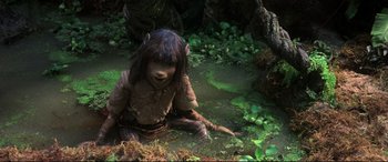 Movie still from “The Dark Crystal” (1982), directed by Frank Oz – A creature sitting on the ground next to some plants; Medium shot, High angle