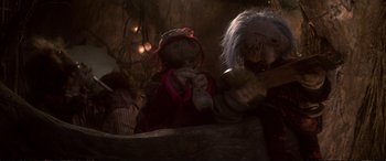Movie still from “The Dark Crystal” (1982), directed by Frank Oz – A group of people sitting next to each other in a room; Medium shot, Low angle