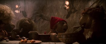 Movie still from “The Dark Crystal” (1982), directed by Frank Oz – A dog wearing a red knitted hat sitting in front of a bowl of food; Close Up shot, Low angle