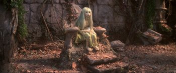 Movie still from “The Dark Crystal” (1982), directed by Frank Oz – A woman sitting on a tree stump in the woods; Wide shot, High angle