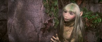 Movie still from “The Dark Crystal” (1982), directed by Frank Oz – A young girl with green hair standing next to a tree; Close Up shot, High angle