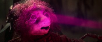 Movie still from “The Dark Crystal” (1982), directed by Frank Oz – The face of a person with purple lighting; Close Up shot, Low angle