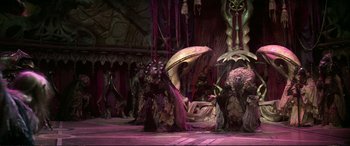 Movie still from “The Dark Crystal” (1982), directed by Frank Oz – A group of people standing on top of a stage; Extreme Wide shot, High angle