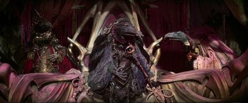 Movie still from “The Dark Crystal” (1982), directed by Frank Oz – A statue of a man in a suit of a horned creature; Medium shot, High angle